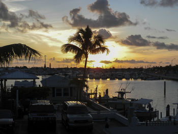 Sailboats moored at harbor against sky during sunset