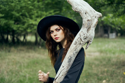 Portrait of young woman standing against trees