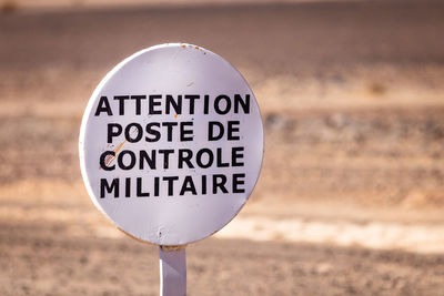 Close-up of information sign on sand