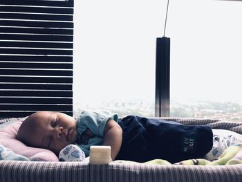 Baby boy sleeping on sofa against window