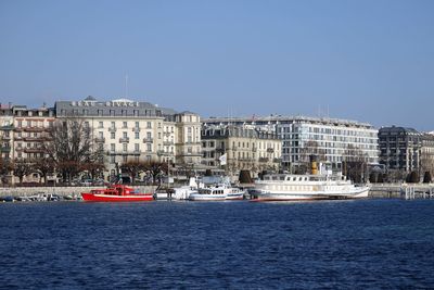 Sailboats in sea against buildings in city