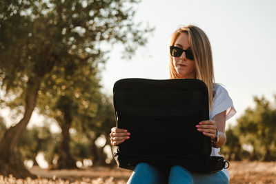 Woman using laptop while sitting at olive orchard