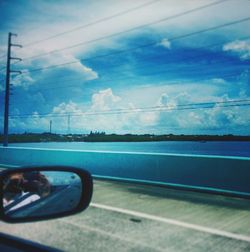 Cars on road against cloudy sky