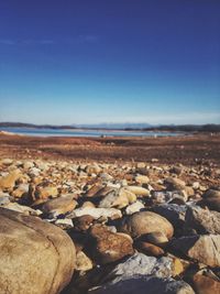 Rocks on beach against blue sky