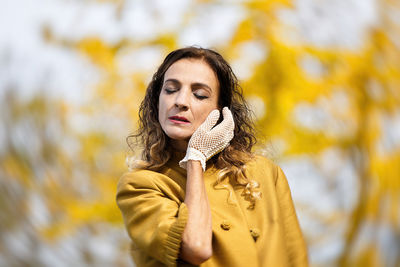 Woman wearing glove standing against autumn trees