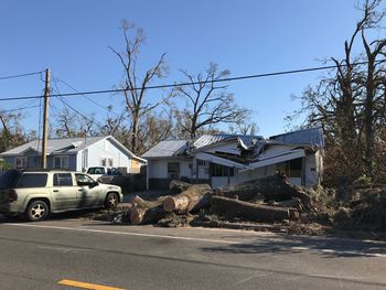 Cars on road by buildings against clear blue sky