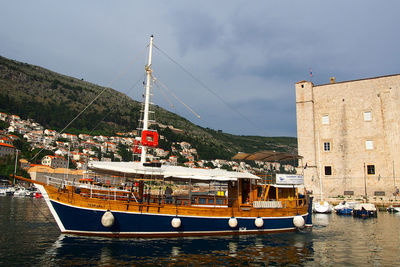 Boats moored in sea against cloudy sky