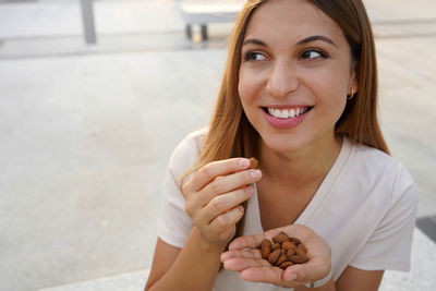 Smiling woman eating almonds outdoors