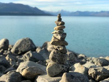 Stack of pebbles by sea against sky