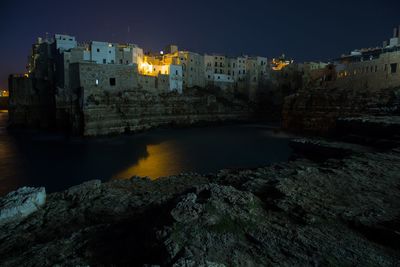 Illuminated buildings by city against sky at night