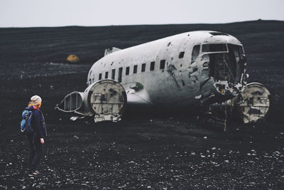 Woman looking at abandoned airplane against sky
