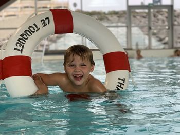 Boy with lifebuoy in the pool smiling