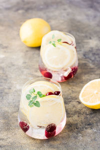 Summer refreshing cold cocktail with lemon, lemon balm and cherry - hard seltzer in glasses