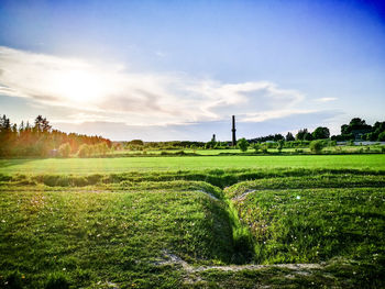 Scenic view of grassy field against cloudy sky