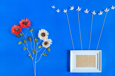Directly above view of flowers by decoration on blue background