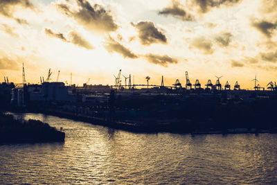 River by city against sky during sunset