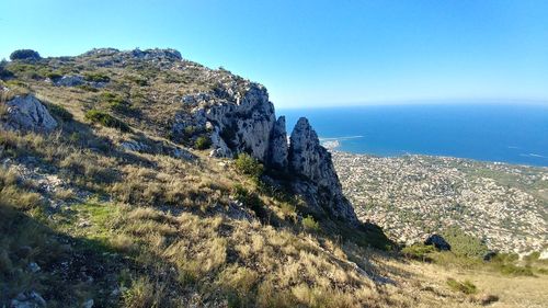 Scenic view of sea and mountains against clear blue sky