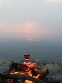 View of fire on landscape against sunset sky