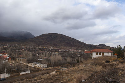 Houses in town by mountains against sky