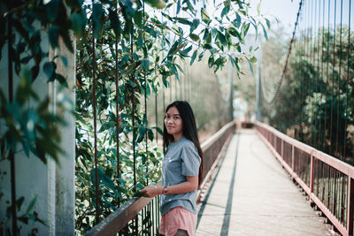 Portrait of woman standing on footbridge