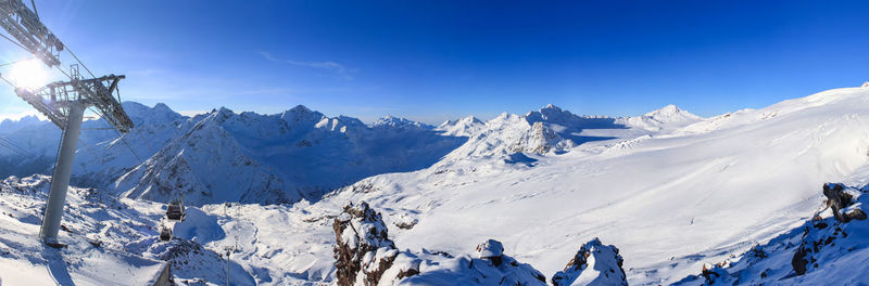 An aerial ropeway of a ski resort against a backdrop of sharp snow-capped peaks