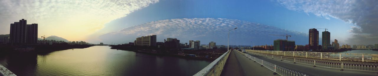 Panoramic view of city by river against sky