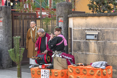 Rear view of people sitting on brick wall