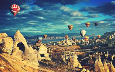 Hot air balloons flying over mountain against sky