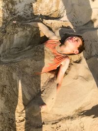 High angle view of boy buried in sand at beach