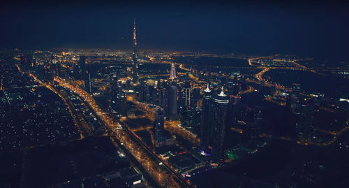 Aerial view of illuminated burj khalifa and cityscape against sky at night