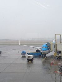 Airplane on airport runway against sky during rainy season