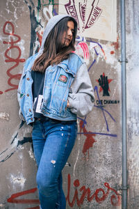 Full length of woman standing against graffiti wall