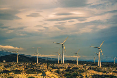 Wind turbines on field against sky