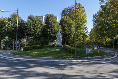 Street by trees against sky in city