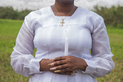 Midsection of a woman holding candle while standing on field