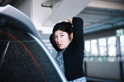 Portrait of young woman looking through car window