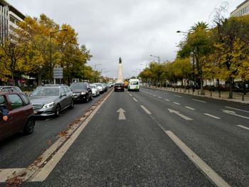 Cars on street in city against sky