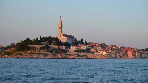 View of buildings by sea against clear sky