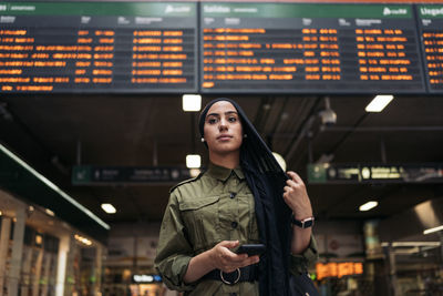 Portrait of young woman standing in city