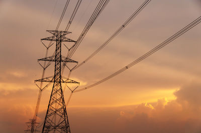 Low angle view of electricity pylon against sky during sunset