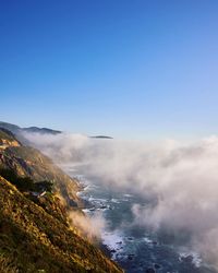 Scenic view of sea and mountains against clear blue sky