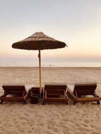 Deck chairs on beach against sky