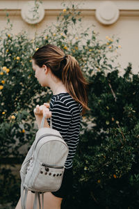 Side view of young woman standing with bag