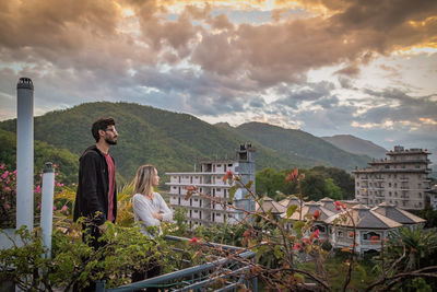 Friends standing at observation point against sky during sunset