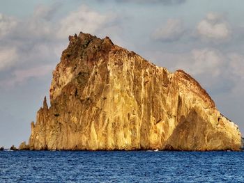 Scenic view of rock formation by sea against sky