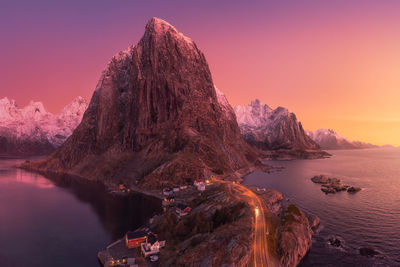 Picturesque scenery from drone of snowy mountains and calm sea under cloudless sky in norway in evening