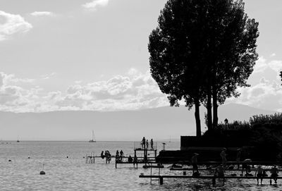 People on lake geneva shore against sky