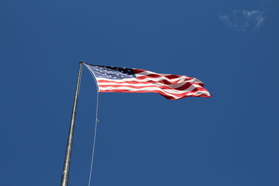 Low angle view of flag against clear blue sky