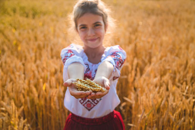 Portrait of girl holding wheat at farm