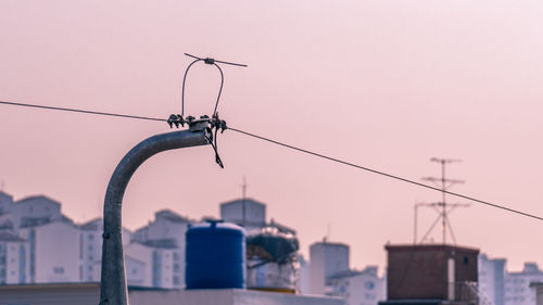 Low angle view of crane in city against sky during sunset